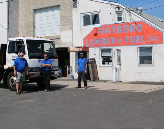 Two men standing in front of a hatboro lumber and fuel co.