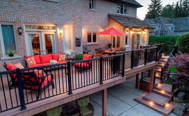 A wooden deck with a couch , chairs , table and grill.