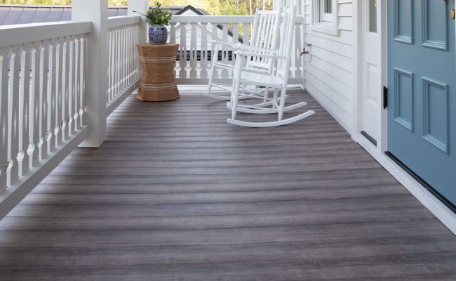 A white railing on a deck with a wicker chair