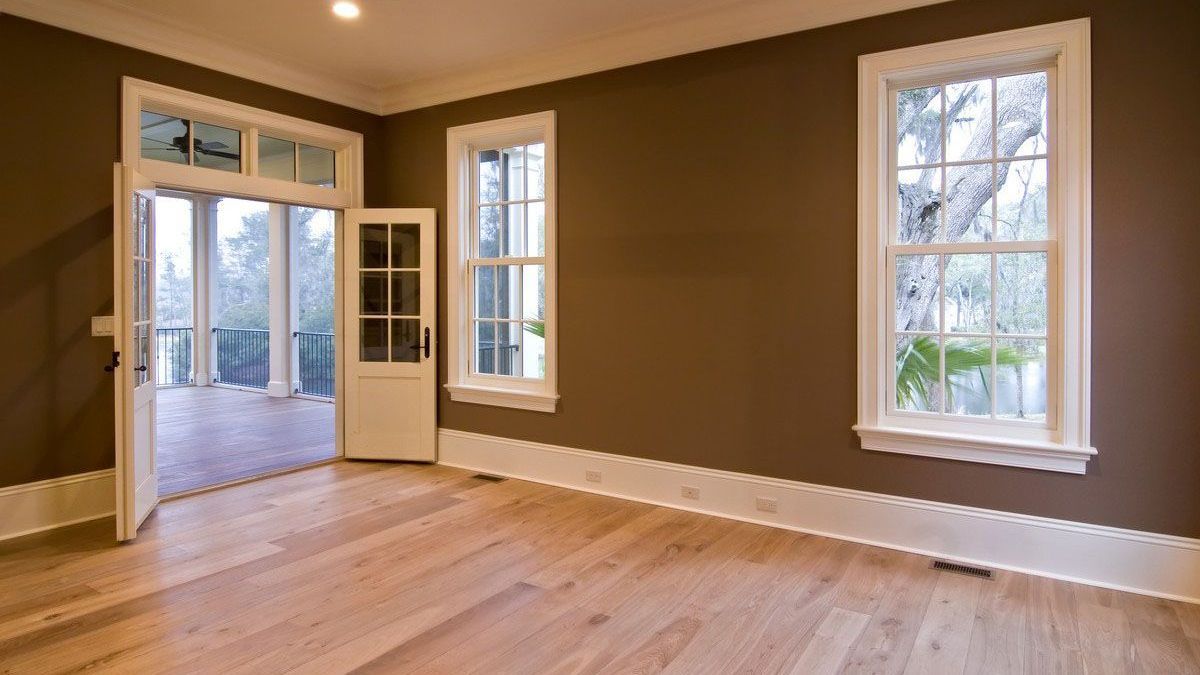 An empty room with hardwood floors and brown walls.