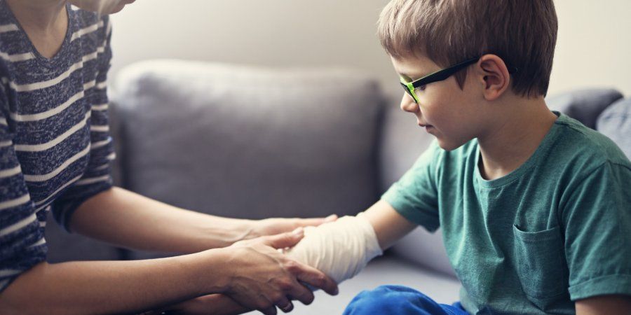 Adult wrapping a bandage around a child’s wrist on a couch