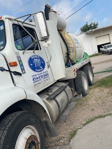White cement mixer truck parked outdoors beside a building under a blue sky.