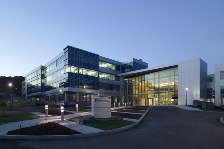 Modern multi-story office building with glass facade; evening.