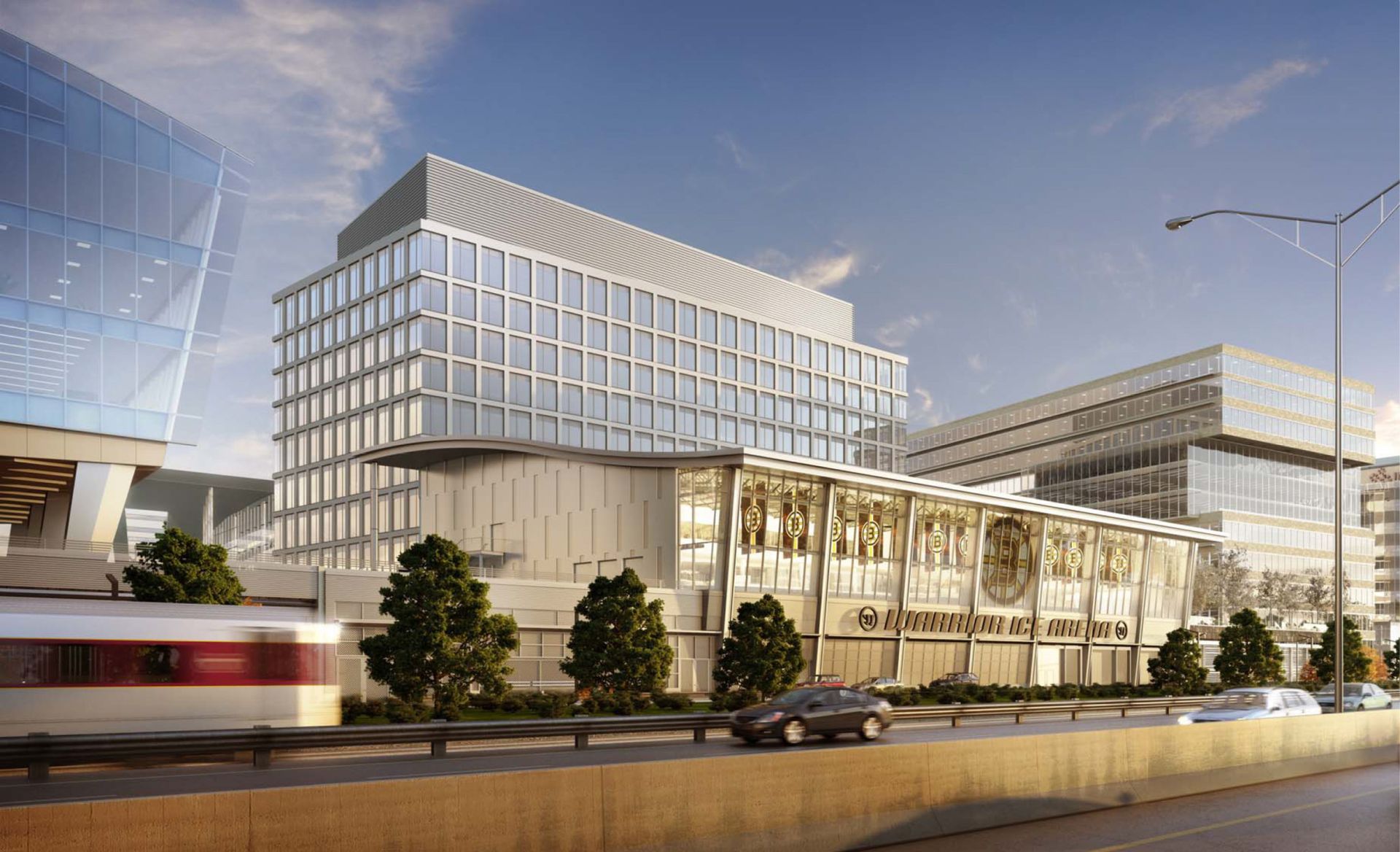 Modern building complex with a light rail train passing by, sunny day.