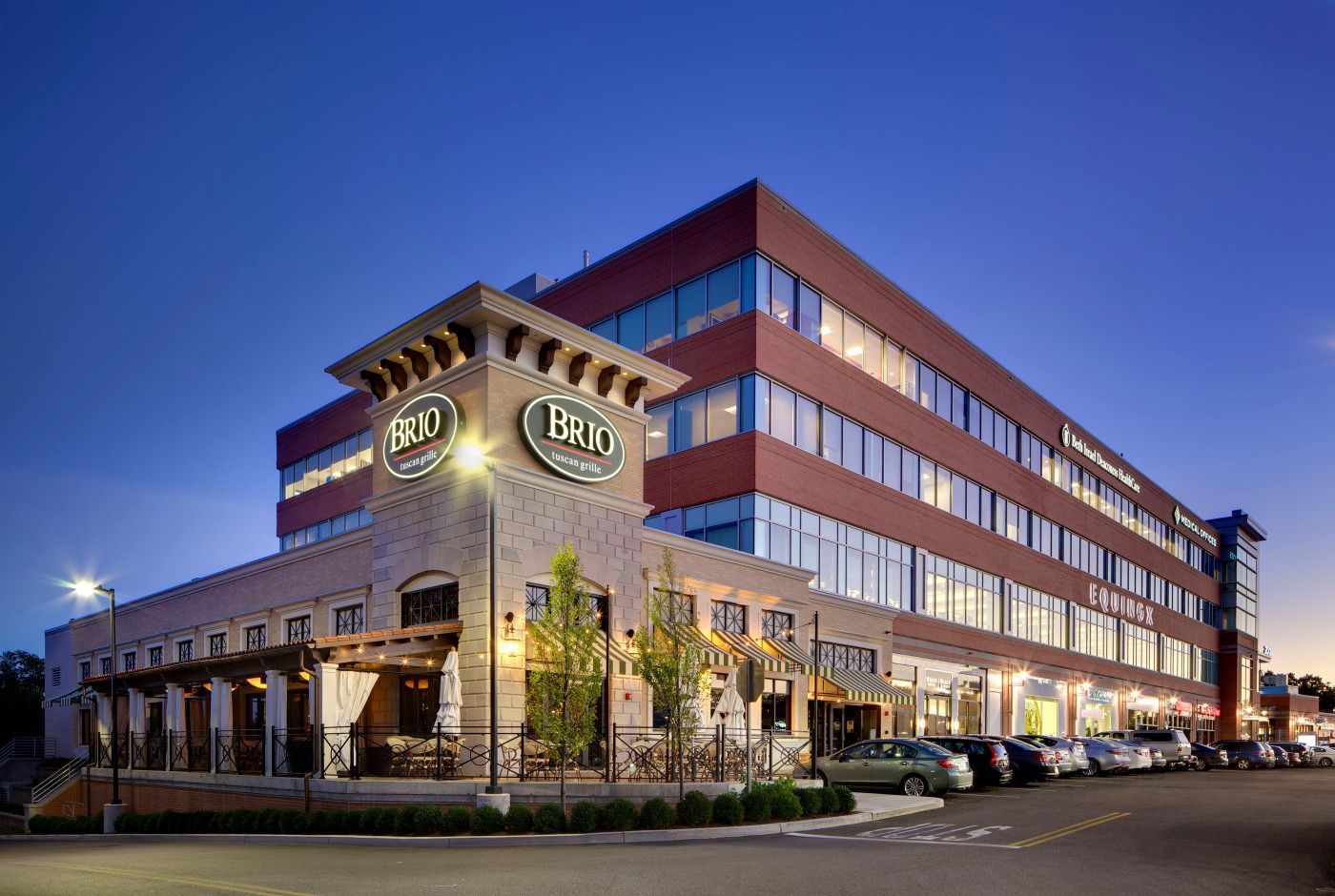 Restaurant and office building at dusk; B&T Brick, red and beige facade, cars parked.