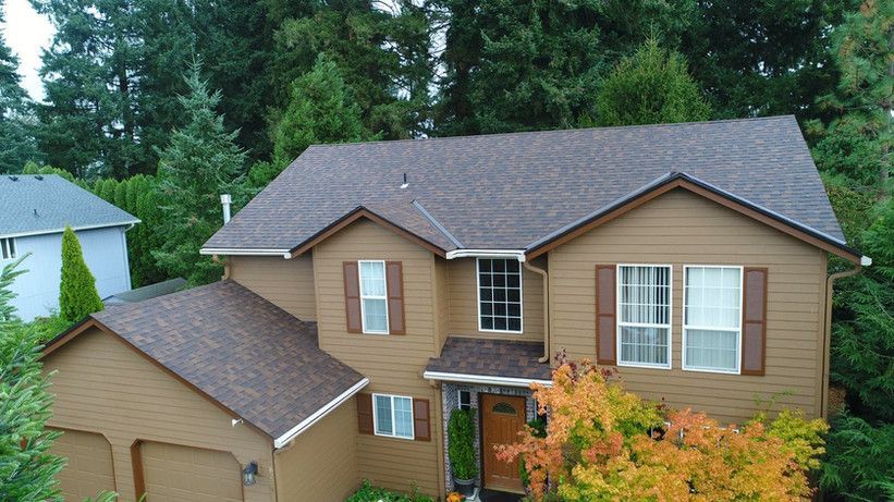 an aerial view of a house with a brown roof surrounded by trees