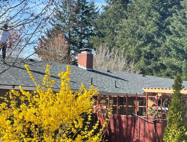 a house with a chimney and yellow flowers in front of it