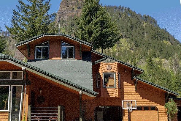 a house with a basketball hoop in front of it and a mountain in the background
