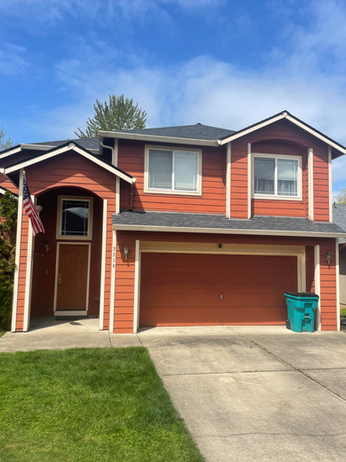 a red house with a green trash can in front of it