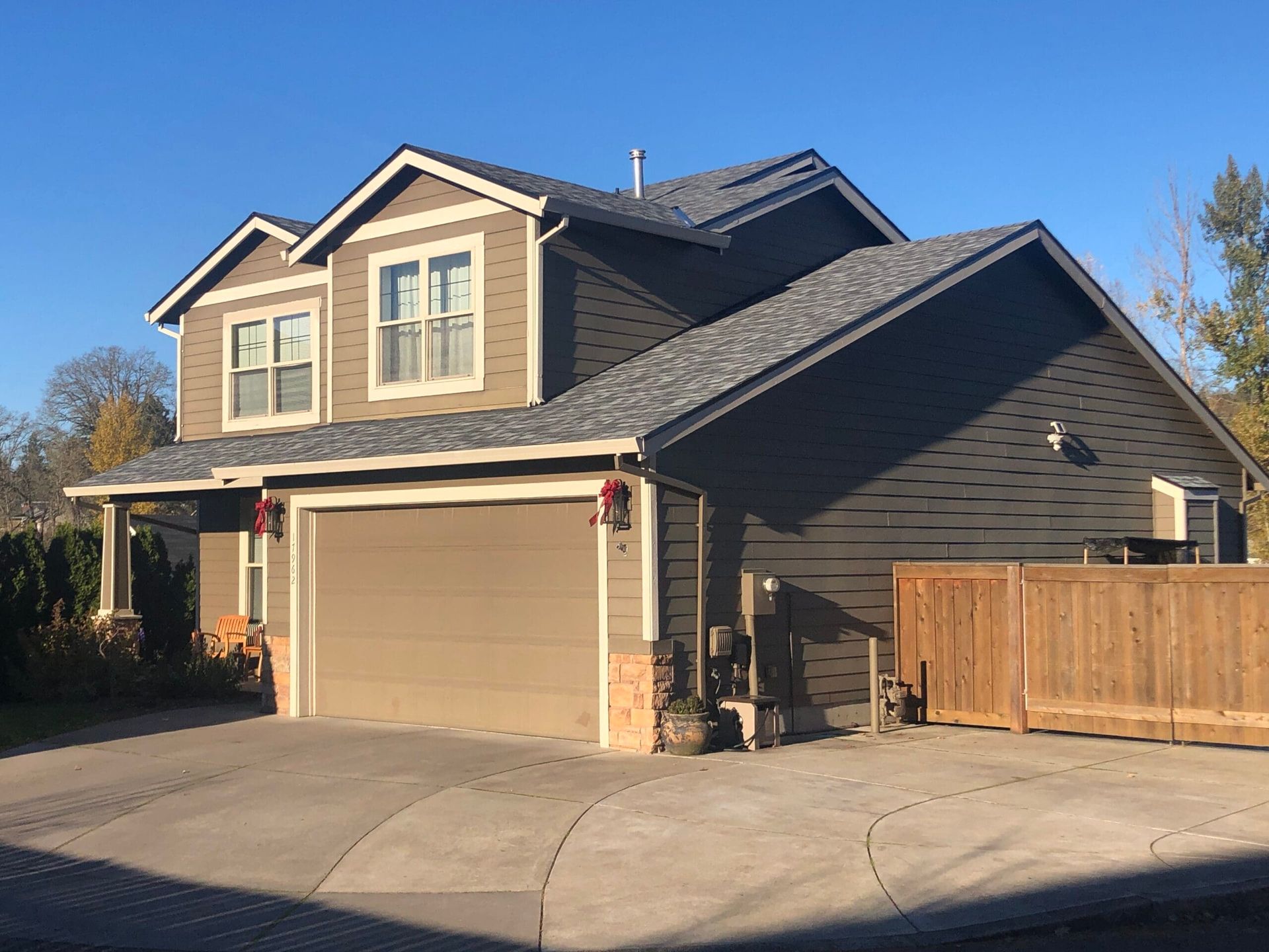 a large house with two garage doors and a wooden fence