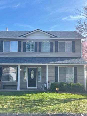 a large house with a blue roof and black shutters is sitting on top of a lush green lawn