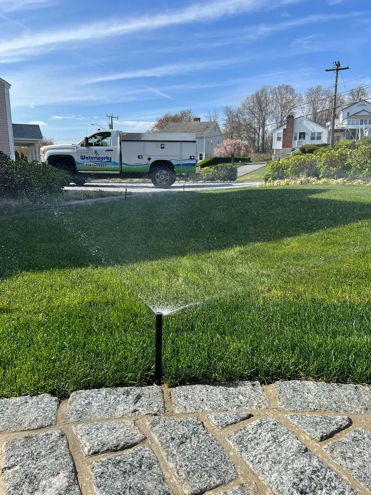 A truck is spraying water on a lush green lawn.