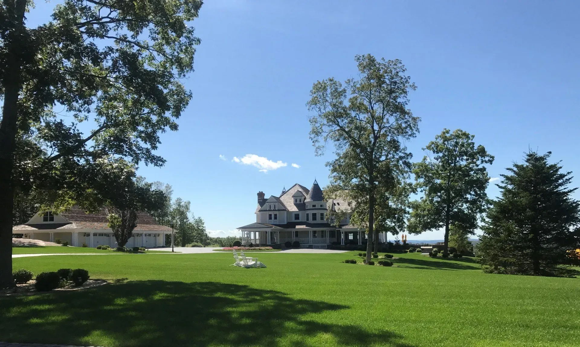 A large house sits in the middle of a lush green field