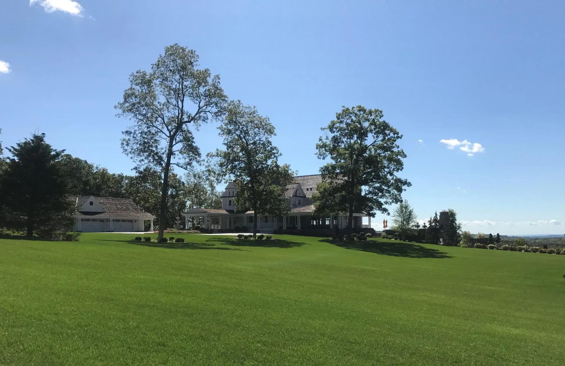 A large house sits in the middle of a lush green field