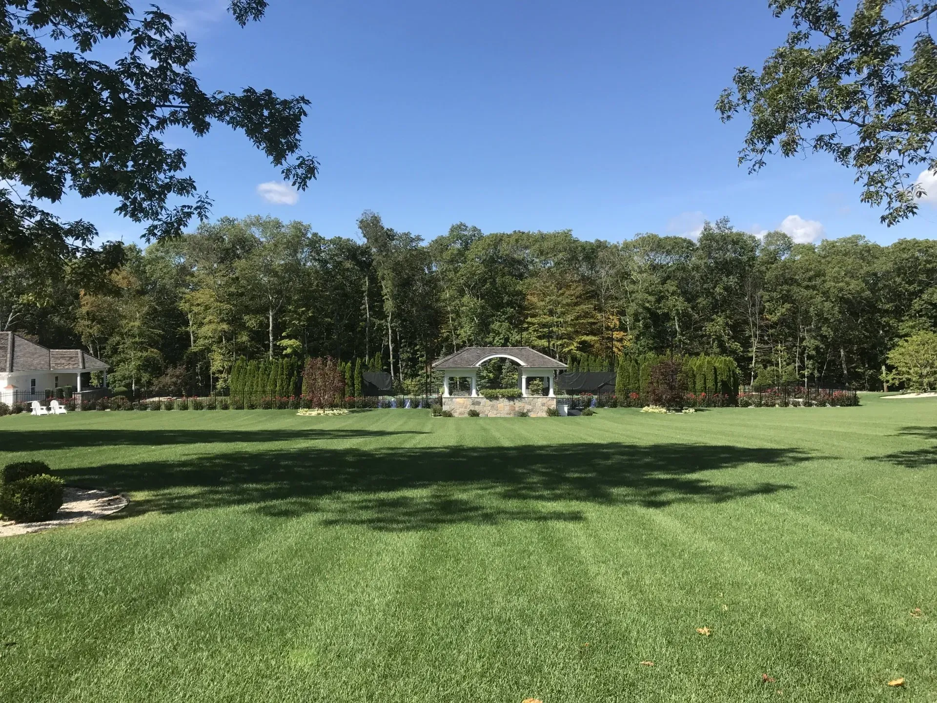A large lush green field with a gazebo in the background