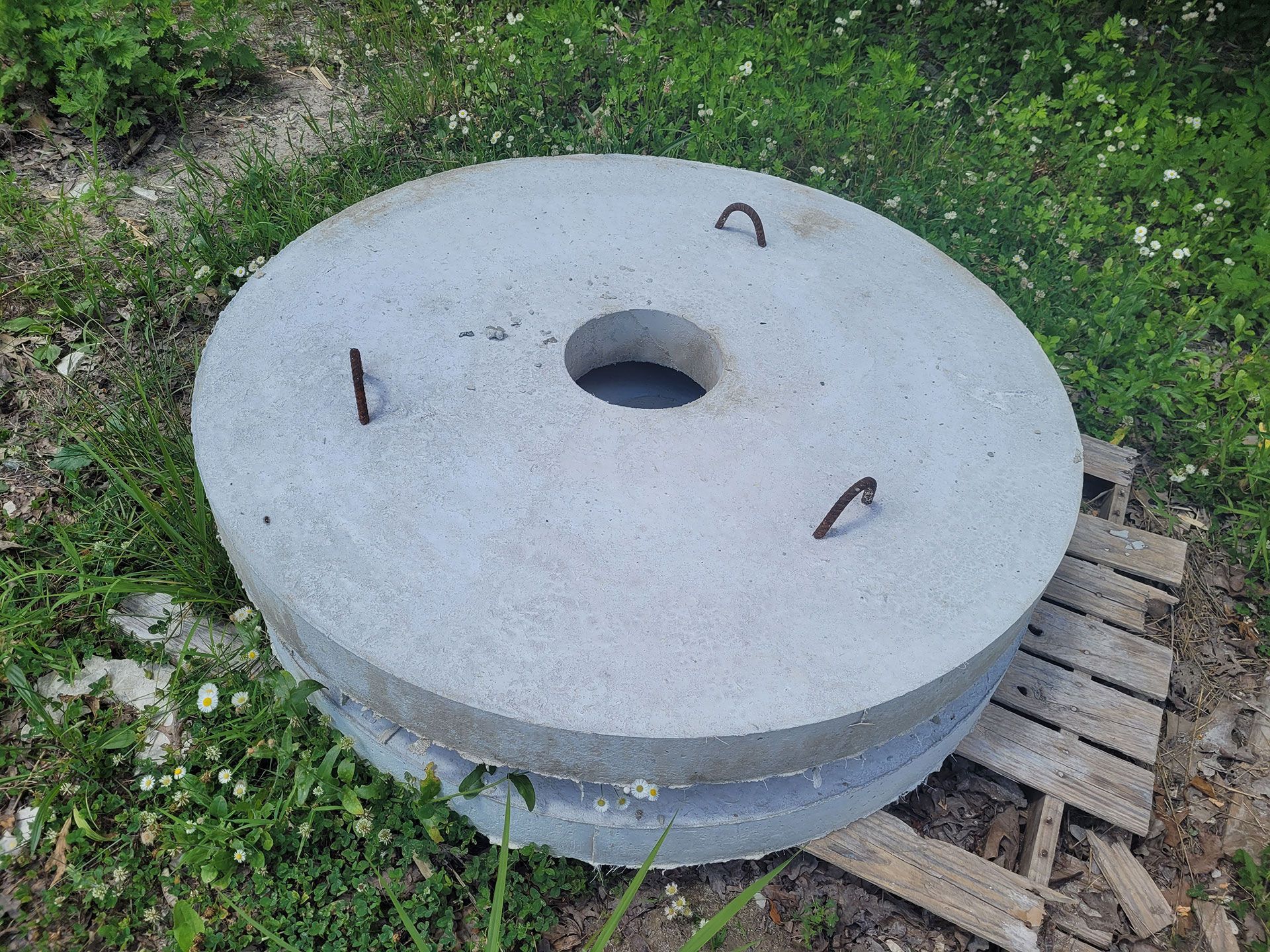 A large concrete circle with a hole in the middle is sitting on top of a wooden pallet