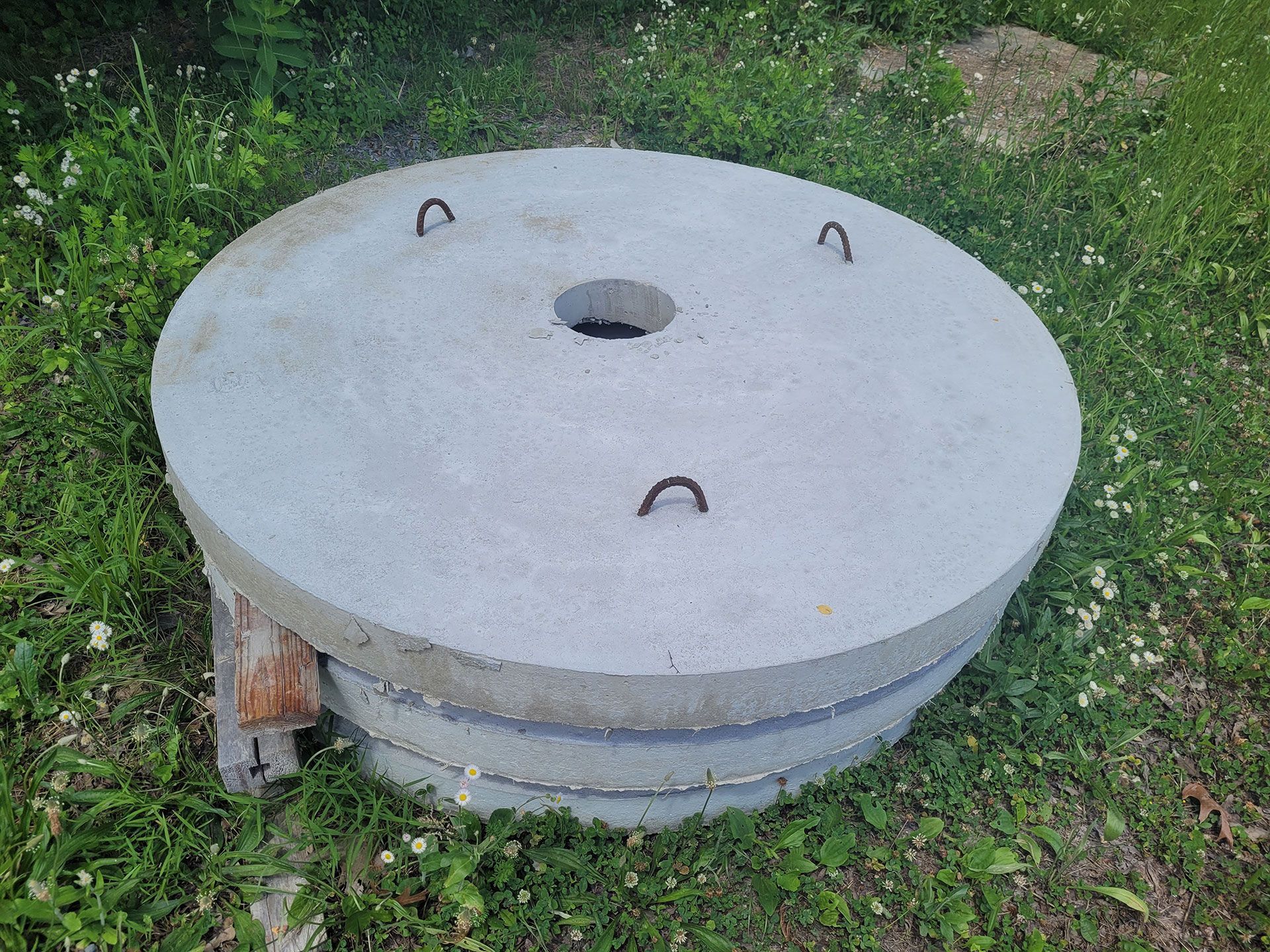 A concrete circle with a hole in the middle is sitting in the grass