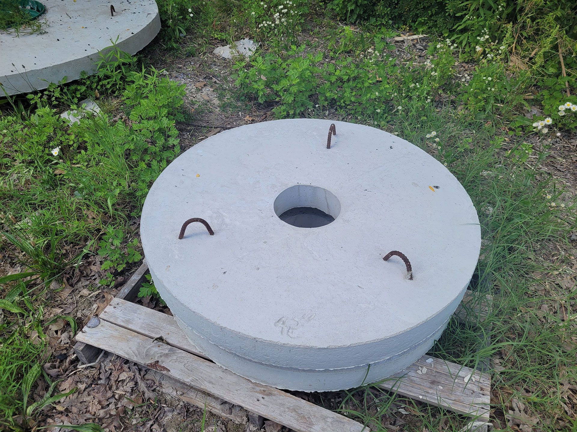 A large concrete circle with a hole in the middle is sitting on top of a wooden pallet