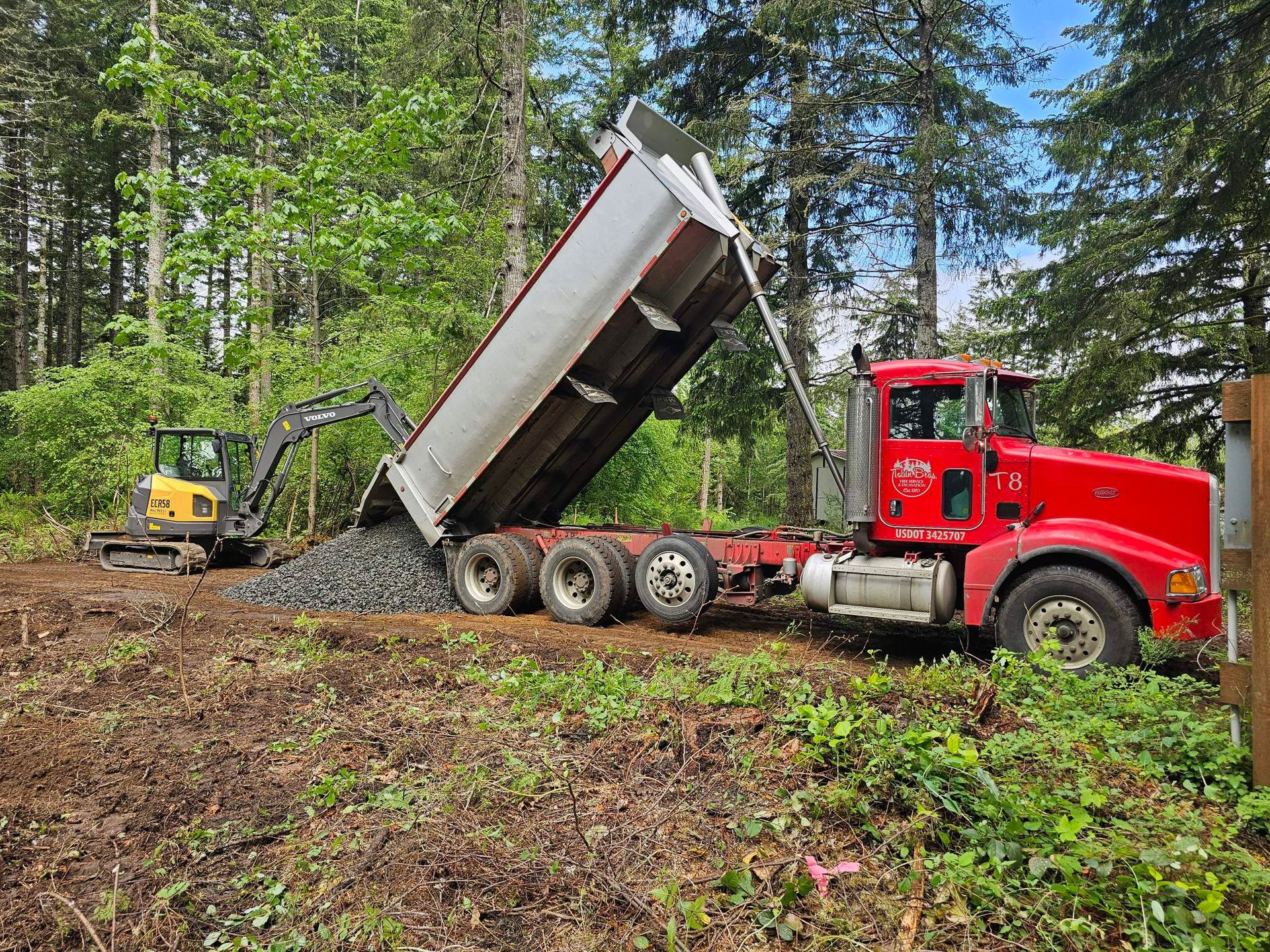 A dump truck is being loaded with gravel in a field