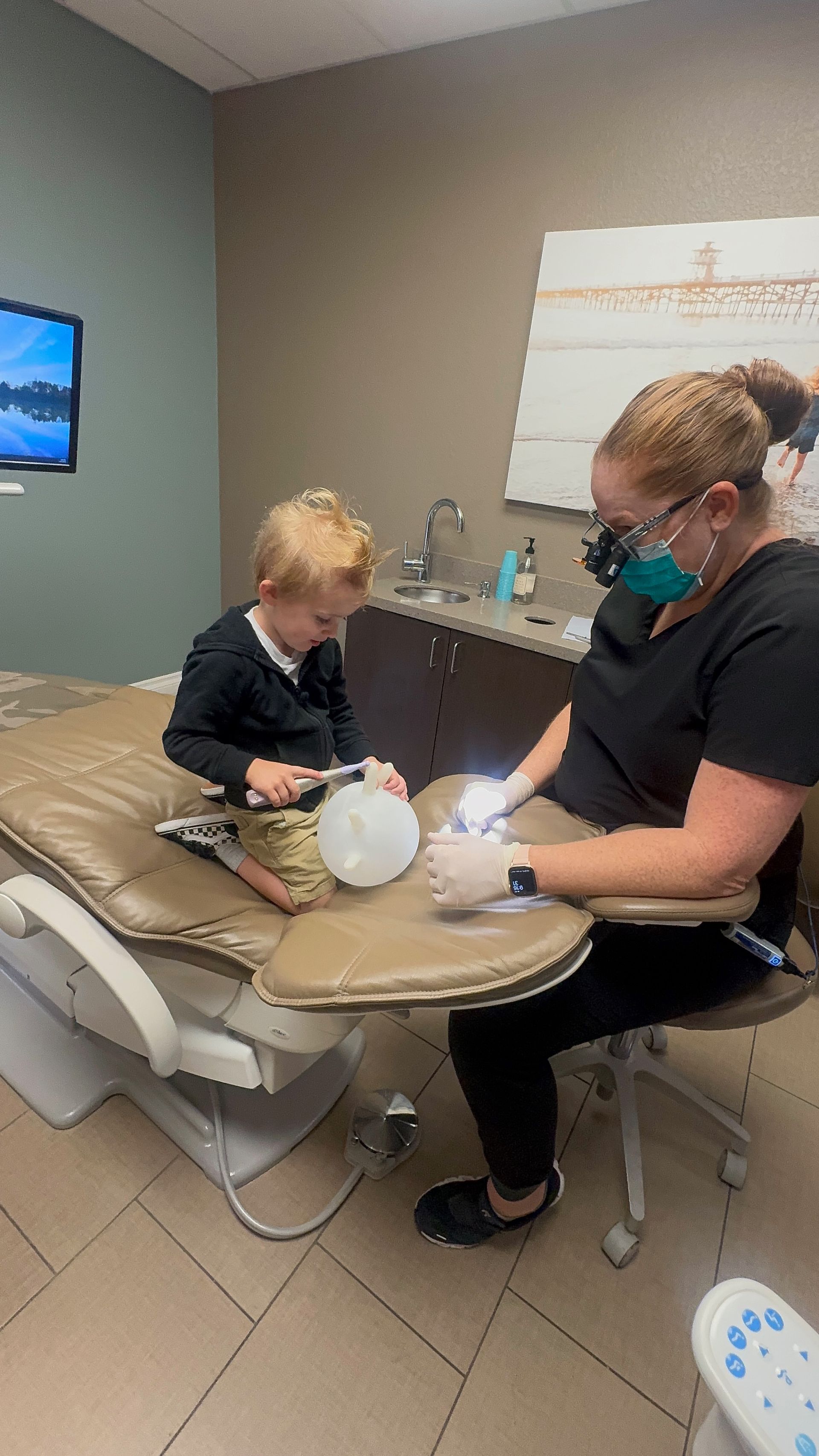 A child playing with an inflated glove, facing a female dentist