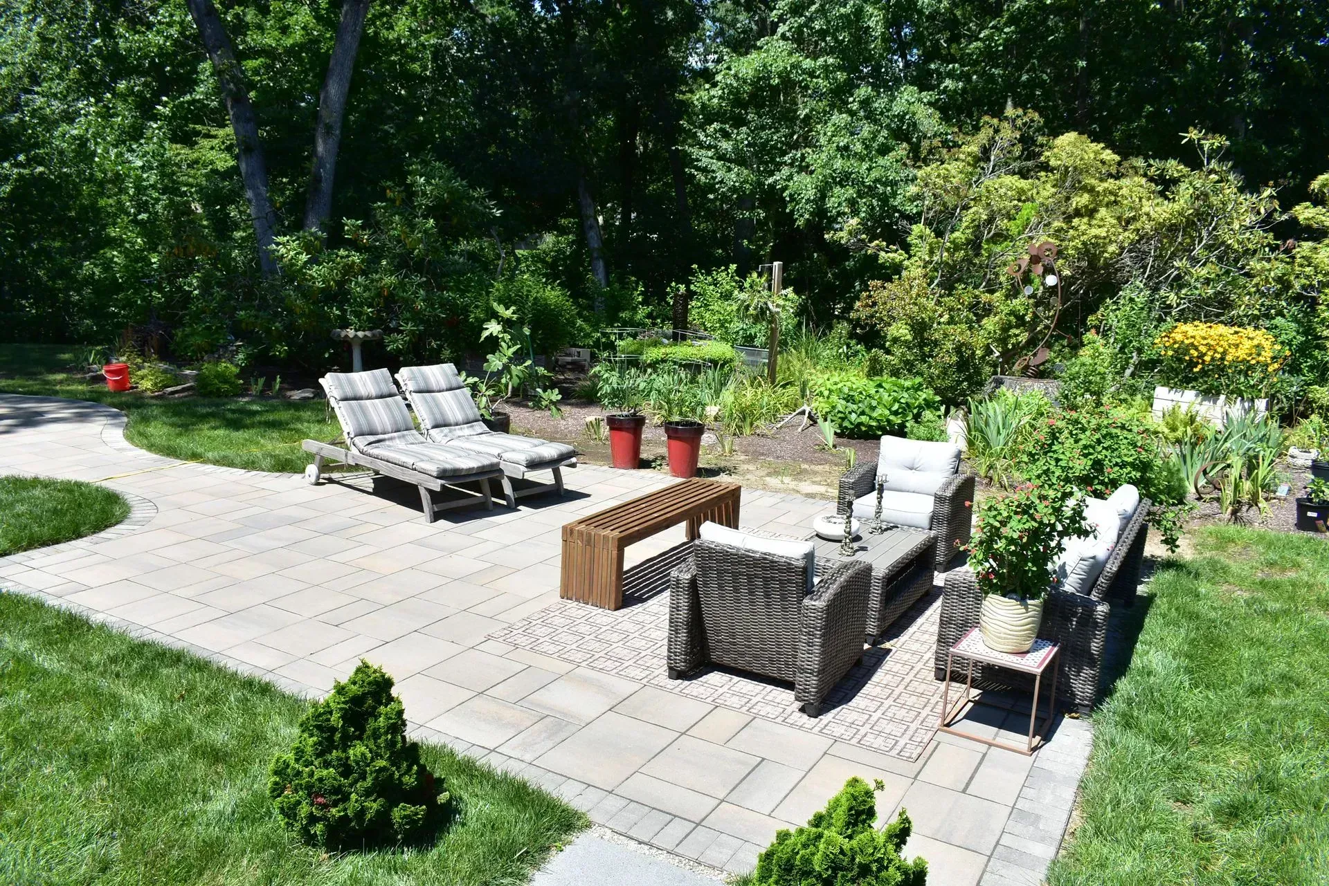 A gravel path winds through a backyard with landscaped mulch beds, various shrubs, two houses, and a small gazebo.
