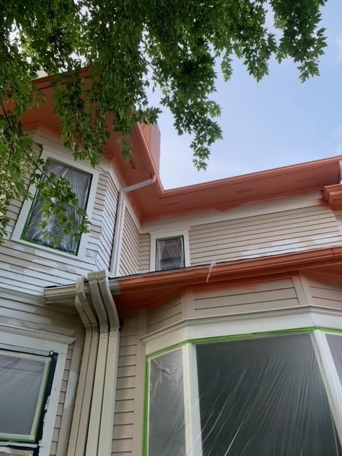 House exterior partially painted; light tan siding, coral trim, masked windows.