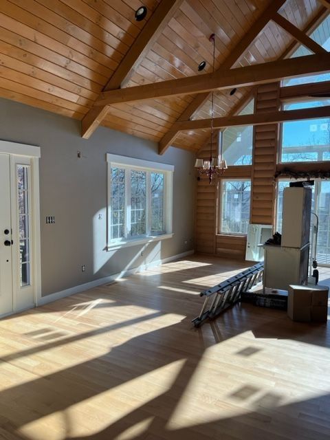 Empty room with wood floors and ceiling, large windows, and a fireplace.