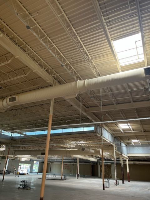 Large, empty store interior with high ceilings, support beams, and skylights.