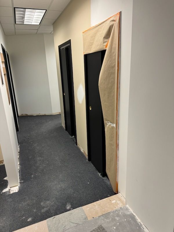 Hallway with doors, one door frame partially covered. White, black, and gray tones.