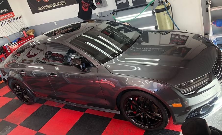 A dark grey Audi sedan parked in a garage with a red and black checkered floor.