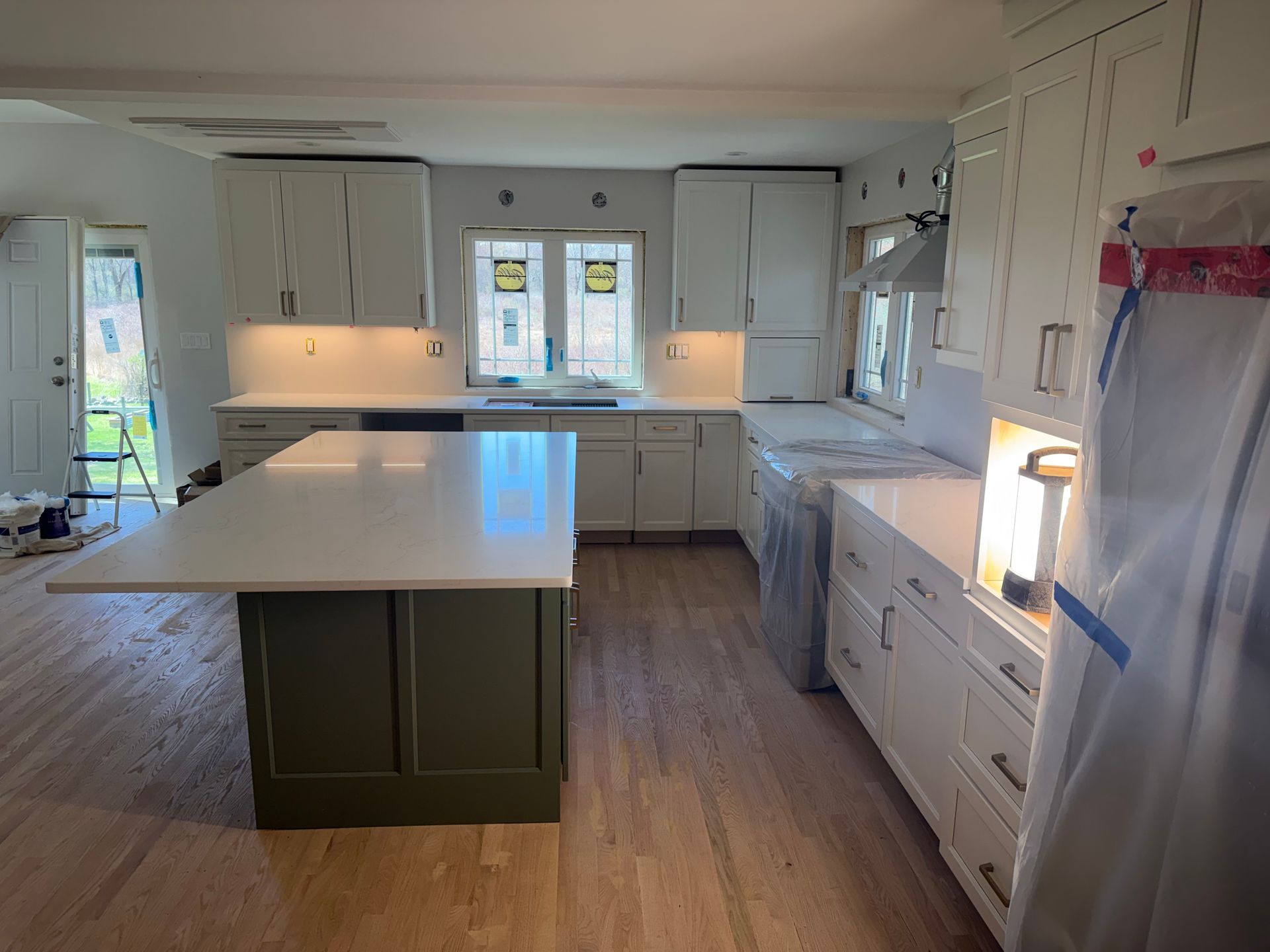 Bright white kitchen with central island, wood floor, and cabinetry along the walls