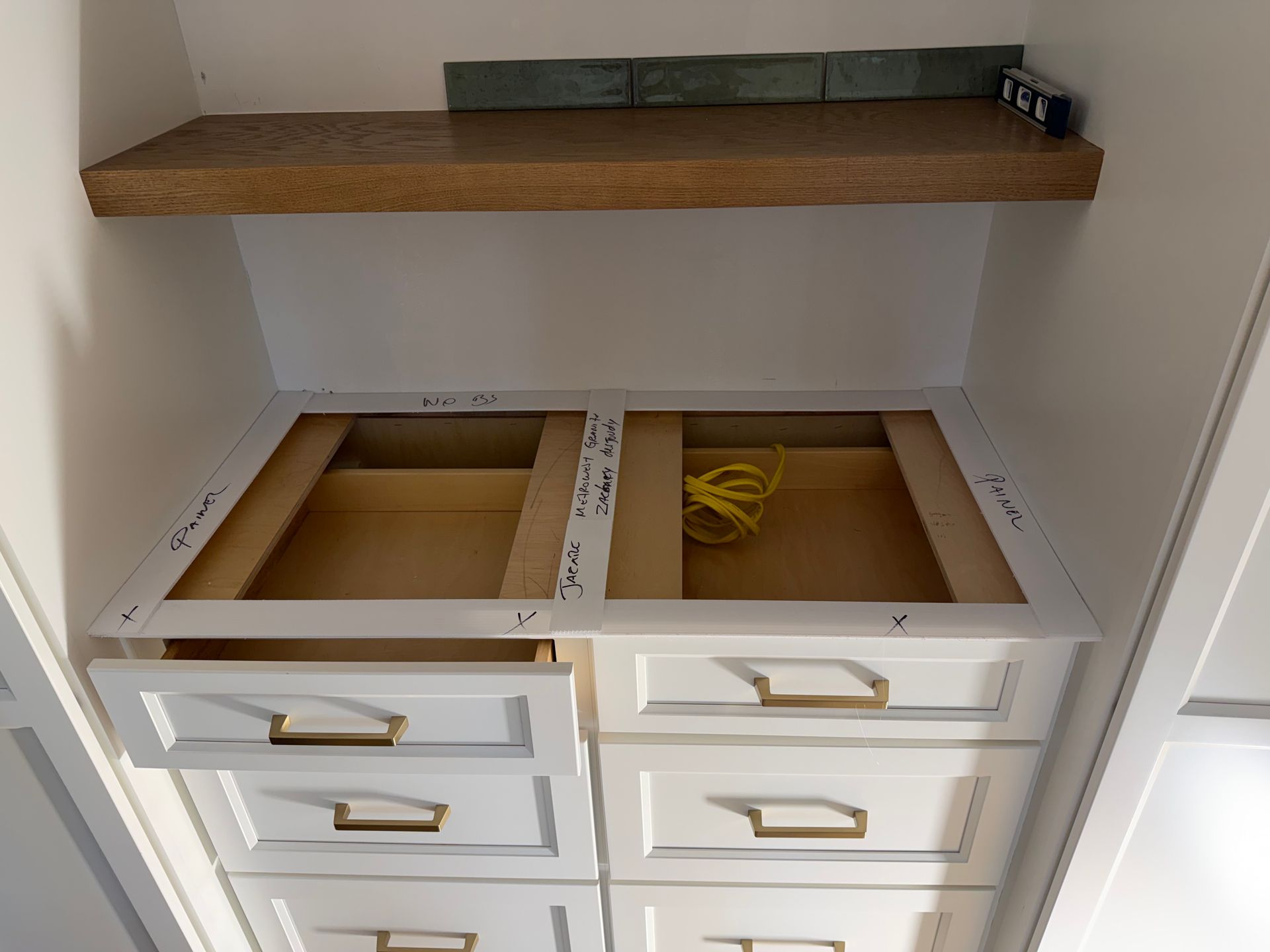 Open white cabinet with shelves and drawer inserts, showing unfinished storage compartments and a wooden top shelf.