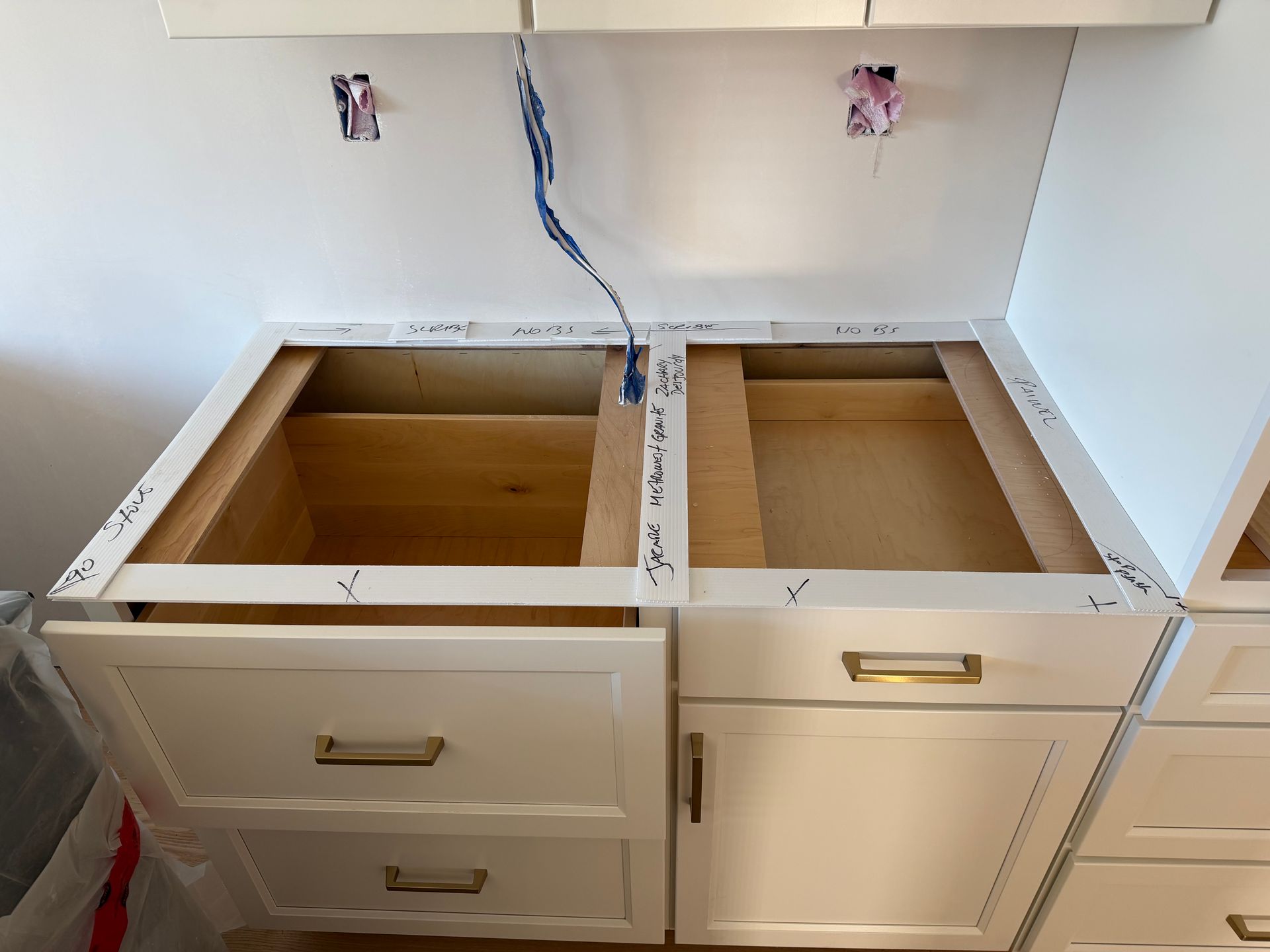 Open bathroom vanity with two sink cutouts, drawer and cabinet fronts removed, and exposed plumbing.