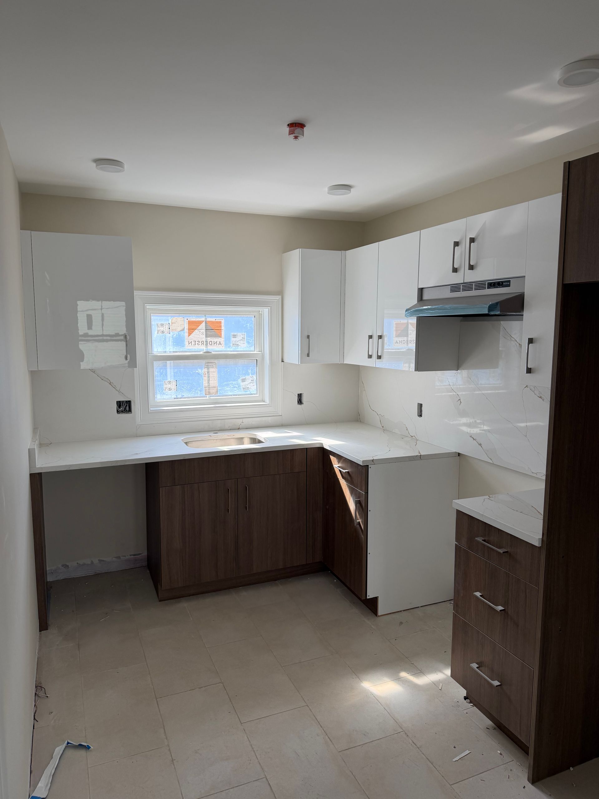 Bright, newly renovated kitchen with white cabinets, dark lower cabinets, and a window over the sink.