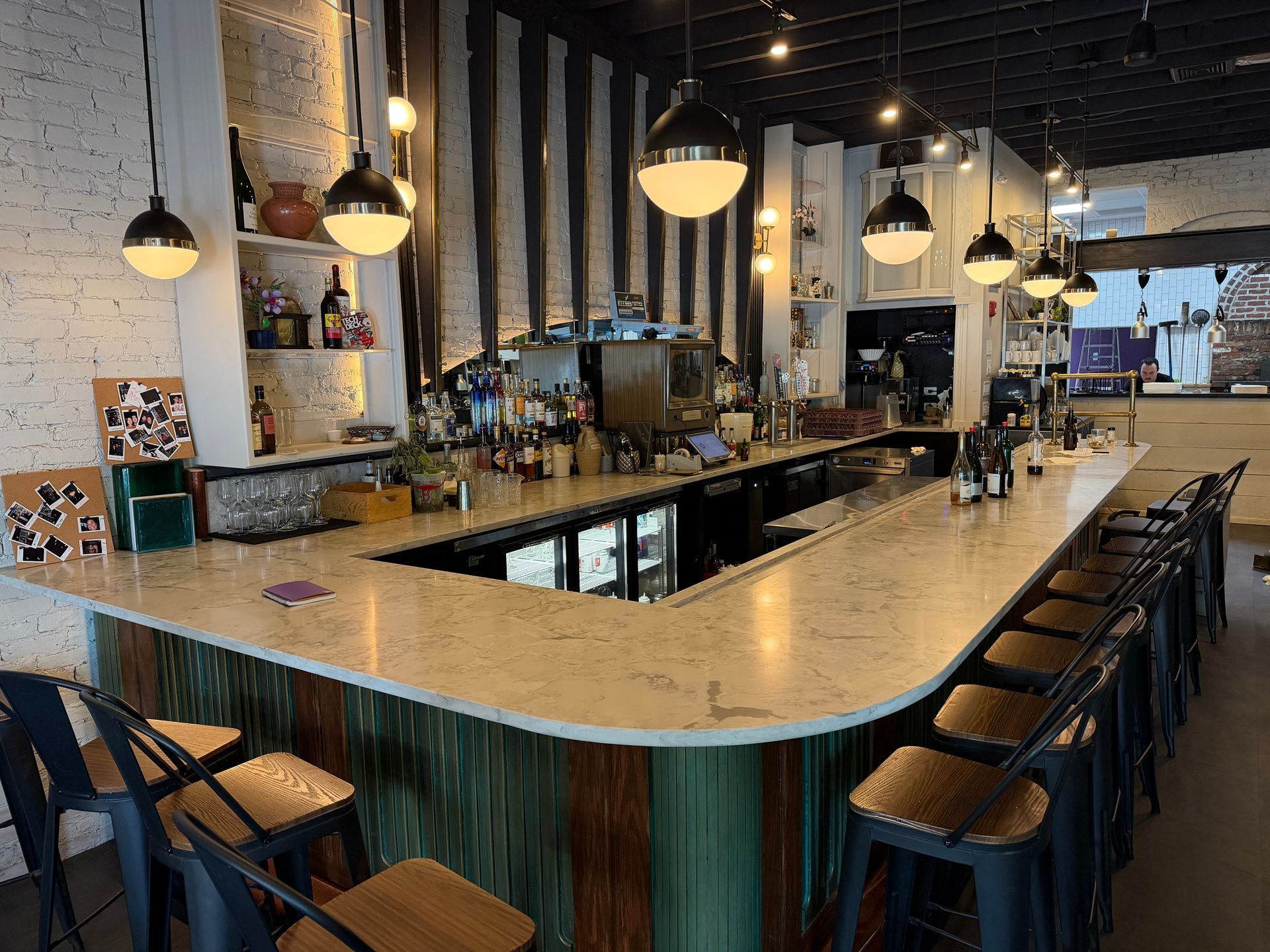 Empty modern bar interior with a long marble counter, pendant lights, and stools