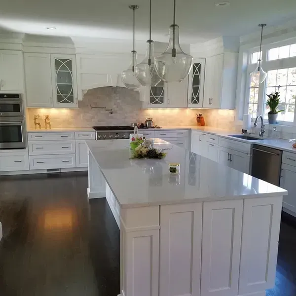 White kitchen with large island and pendant lights.