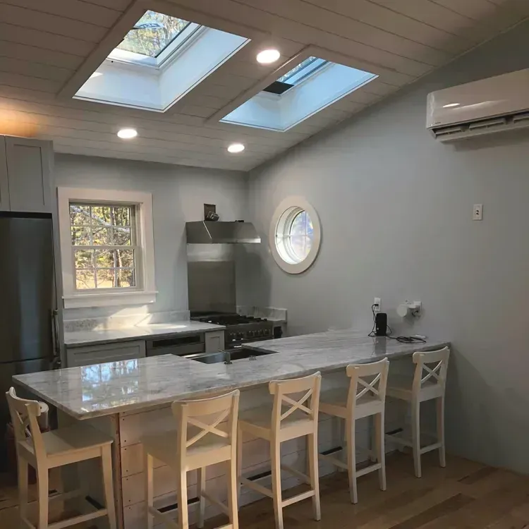 Kitchen with skylights, island, stainless steel appliances, and light blue walls.