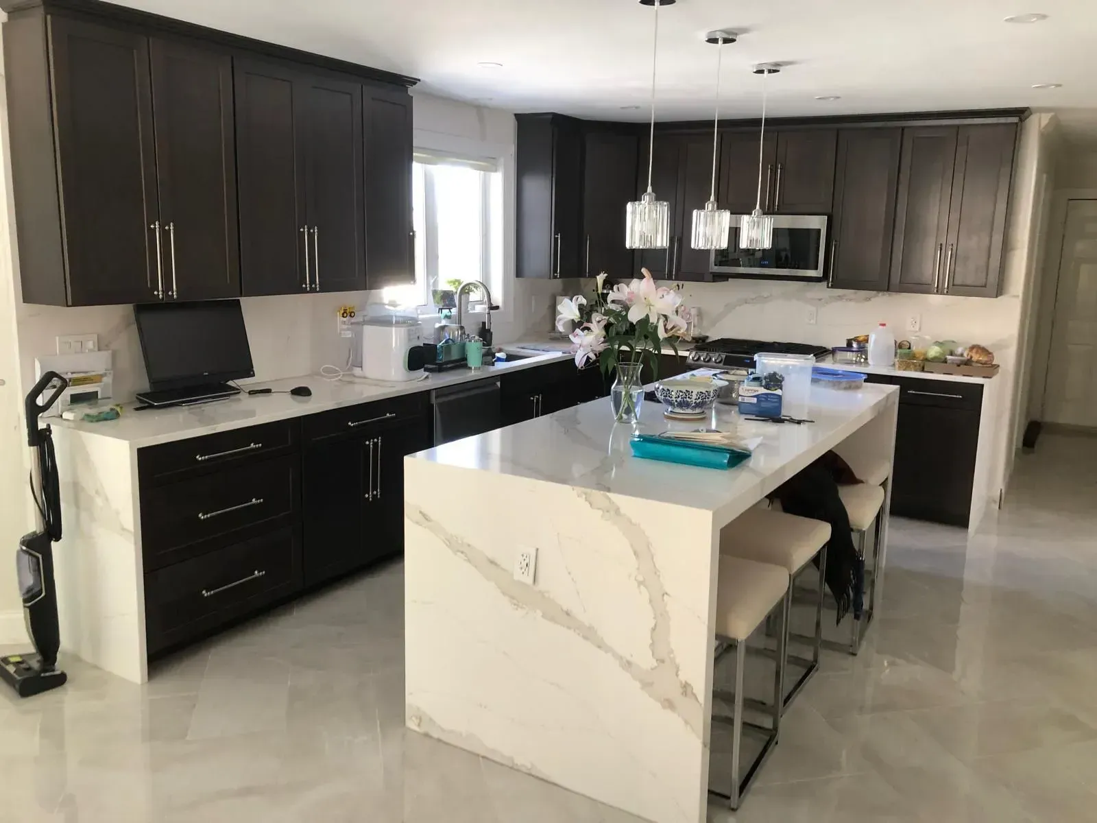 Modern kitchen with dark brown cabinets, white countertops, and an island with seating.