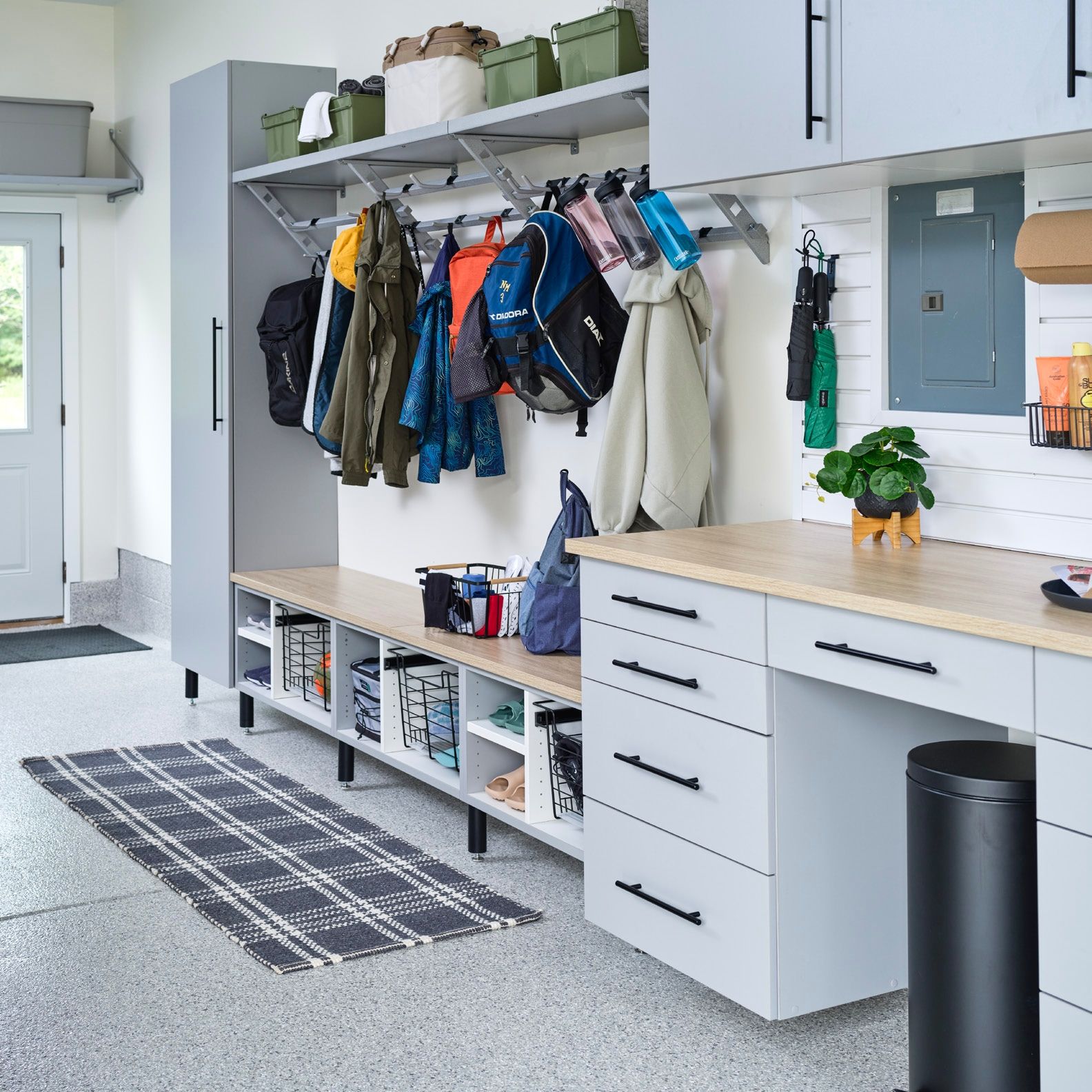 Bright mudroom with coats on hooks, white cabinets, bench storage, and a striped runner rug.