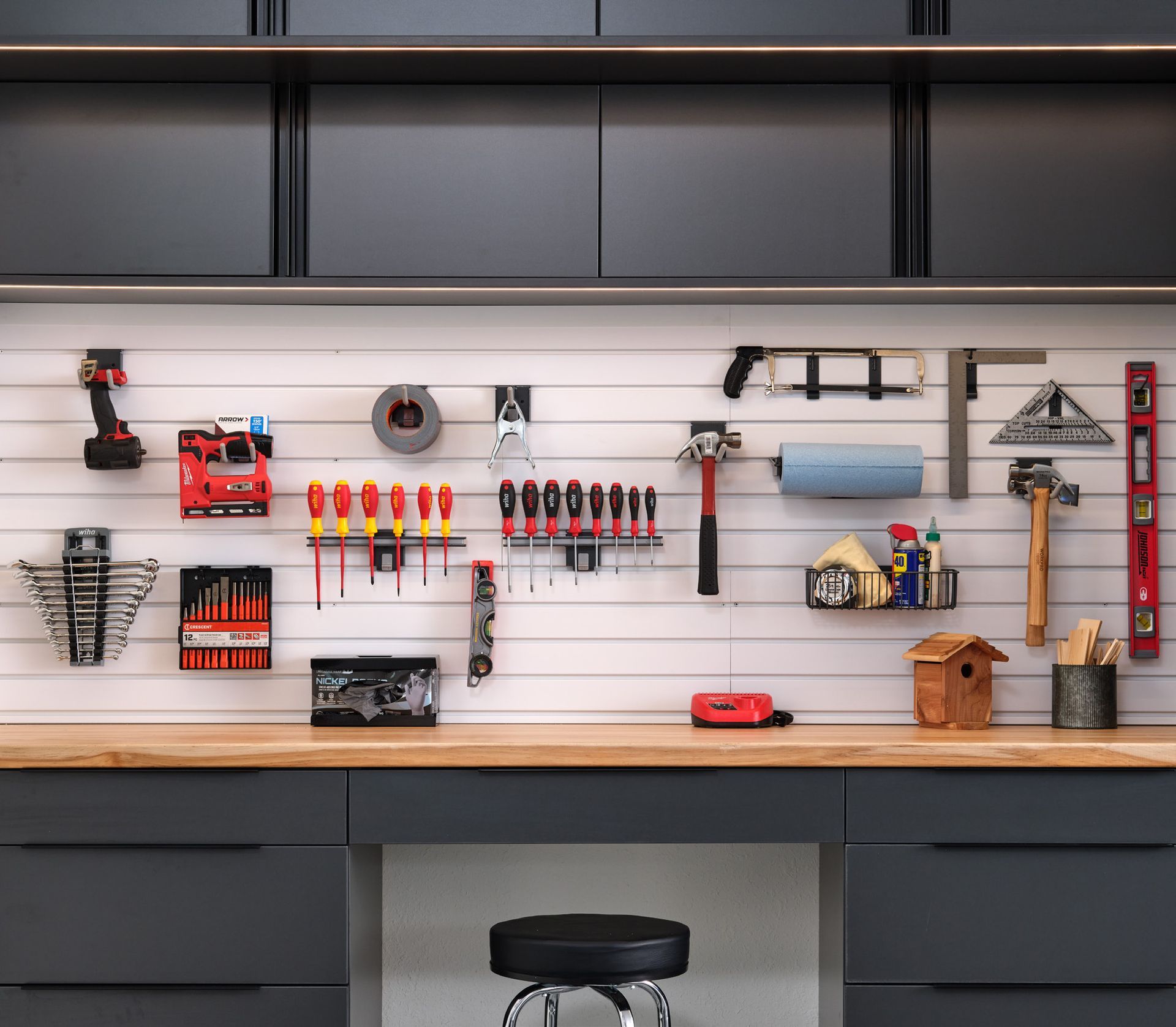 Wall-mounted tools and organizers above a workbench in a tidy garage workshop.