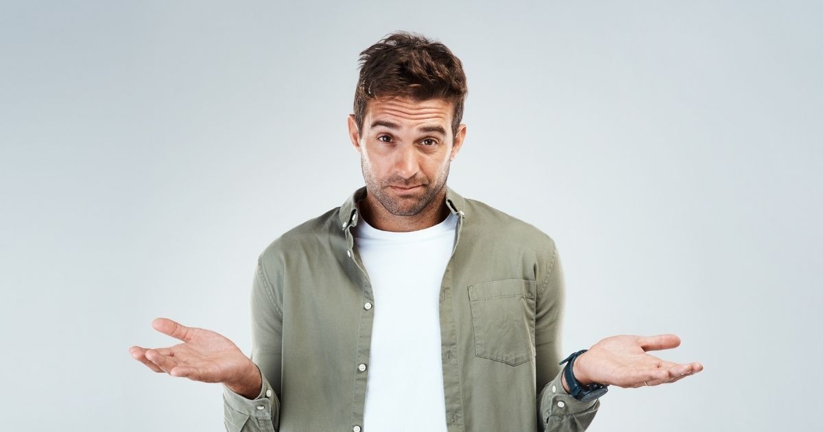 Man shrugging with both palms up against a light gray background