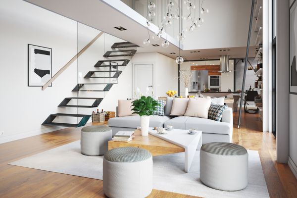 Modern loft living room with white sofa, round ottomans, wood floors, and open staircase