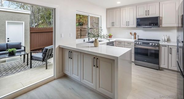 Kitchen with island, light cabinets, and sliding door to patio with seating.
