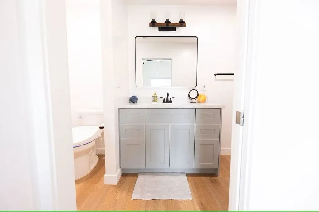 Bathroom interior with gray vanity, large mirror, and toilet visible.
