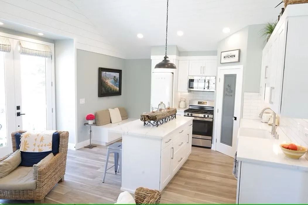 Bright white kitchen with island, seating area, and light gray walls.
