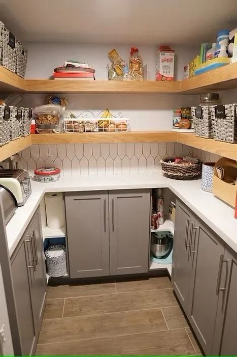 U-shaped pantry with grey cabinets, light wood shelves, and white countertop. Tile backsplash and food storage visible.