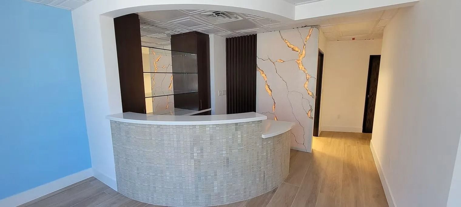 Bar area with a curved counter and a decorative ceiling fixture, with a blue wall and a hallway.