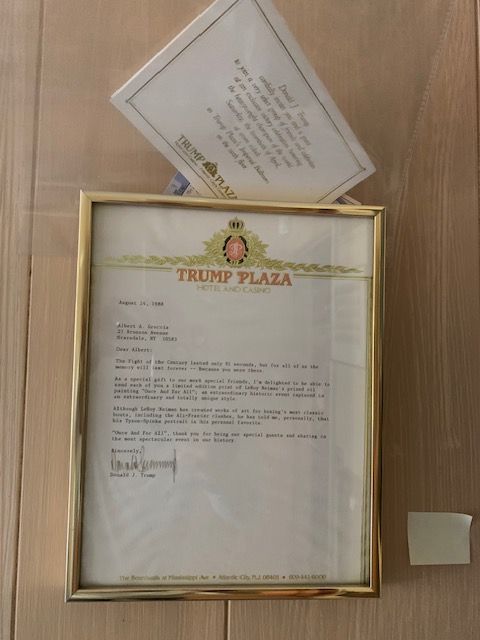 Framed letter on a wall below a tilted envelope, both with Trump Plaza letterhead