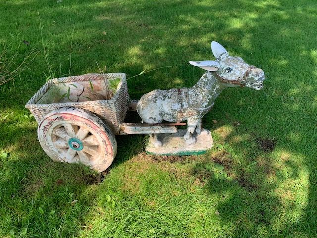 Weathered stone donkey cart sculpture on green grass