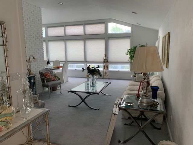 Bright living room with large windows, white sofa, glass coffee table, and side lamps